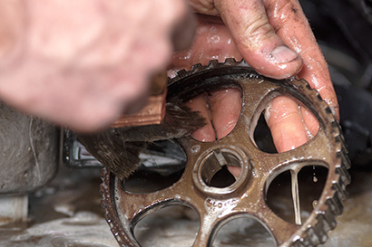 Car mechanic is cleaning and mantaining gear .