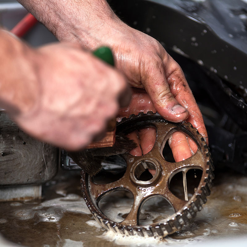 Car mechanic is cleaning and mantaining gear .